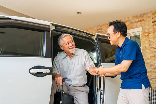Man helping a smiling senior gentleman out of a van