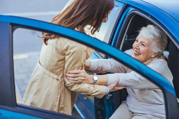 Caregiver gently helping an elderly woman out of a car