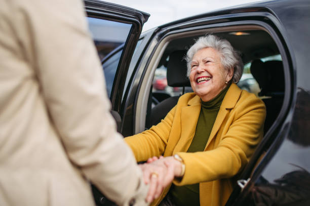 Elderly woman smiling as she is helped into a vehicle